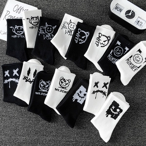 Black and white mid-calf cotton sports socks with graffiti monster prints in a flat lay view