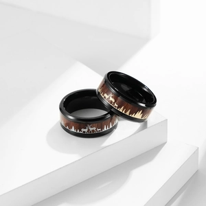 Macro detail showing laser-engraved forest and elk patterns on wood inlay steel rings