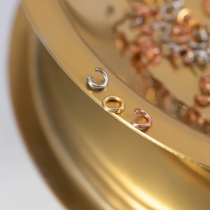 DIY jewelry connectors in gold, silver, and rose gold finishes on a gold tray edge