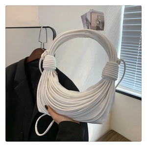 Detail of white pleated handbag with architectural knotted lines and large round handle