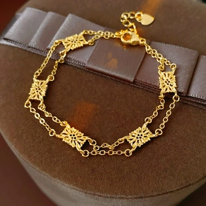 Detail of vintage gold flower pendant on double-layer chain bracelet over velvet