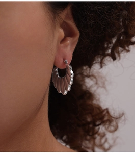 Close-up of silver scalloped hoop earrings with polished wavy texture on female model