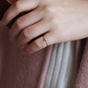 Close-up of minimalist heart ring in 18K gold plating on finger with zircon detail