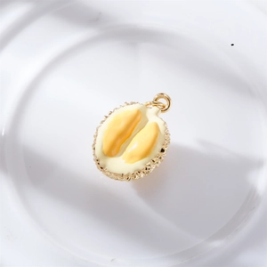 Detail shot of a golden durian pendant with yellow enamel inlay on white ceramic tray
