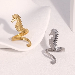 Detailed view of seahorse-shaped open rings in gold and silver finish on display