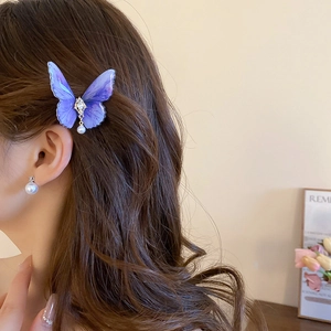 Détail d'une pince à cheveux papillon en acrylique violet avec strass et perle pendante