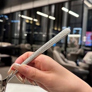 Détail d'une main tenant un manche de cuillère en acier inoxydable à texture martelée