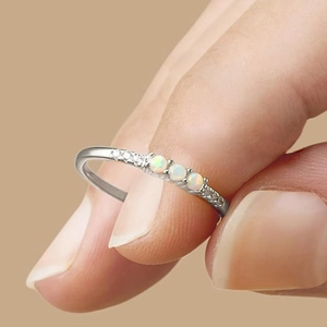 Nahaufnahme eines minimalistischen Silber-Opal-Rings mit Diamanten zwischen den Fingern