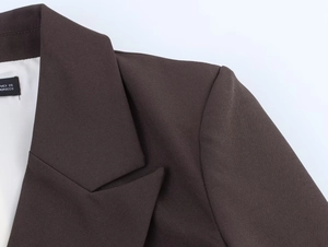 Close-up of padded shoulder and lapel detail on a dark brown double-breasted blazer