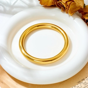 Nahaufnahme eines hochglanzpolierten goldenen Armreifs auf einem weißen Keramikteller