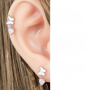 Close-up of butterfly stud earring with white enamel and dangling heart zircon stone