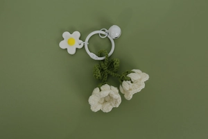 Detailed view of handmade crochet lily of the valley keychain with bell on green background