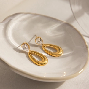 Makroansicht von goldenen Tropfenohrringen mit Zirkonia auf einer Muschelschale