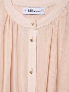 Close-up of pleated apricot chiffon blouse featuring elegant gold buttons and stand collar