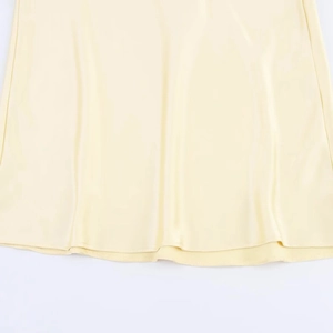 Gros plan détaillé de l'ourlet en satin jaune pâle lisse sur cette robe élégante