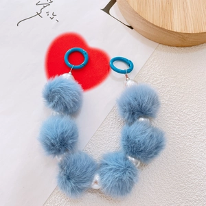 Detail of sky blue fluffy pom pom phone chain with white pearls and round spring buckles