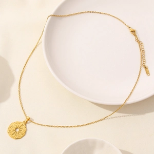 Dettaglio della collana con ciondolo luna sole dorata e catena regolabile su vassoio