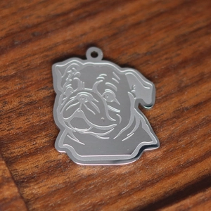 Silver stainless steel pug dog head pendant charm on dark wooden surface close-up view