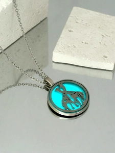 Detail of silver round giraffe pendant necklace with vibrant turquoise glowing resin inlay