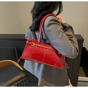 Detailed close-up of a stylish red glossy leather handbag with elegant gold-tone hardware