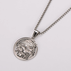 Macro shot of silver stainless steel pendant featuring a religious relief and box chain
