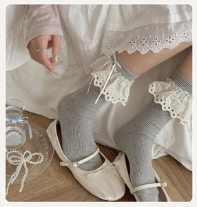 Close-up of grey ribbed socks with white lace trim and bow in balletcore aesthetic
