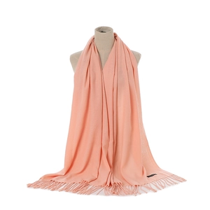 Detail of peach cashmere-like scarf showing soft knit texture, fringes and black label