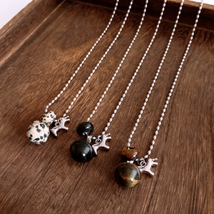Detailed view of bead chains with tiger eye, onyx, and jasper horse pendants on wood