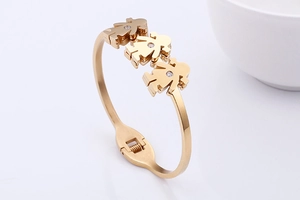 Close-up of gold open bangle featuring three hollow girl charms with sparkling zircon stone