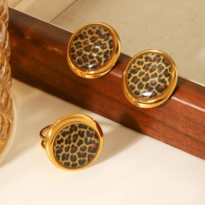 Detail of 18K gold-plated geometric earring and leopard print ring set on wood