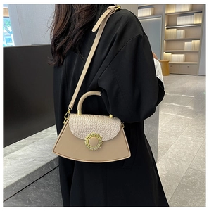 Details der beigen Handtasche mit Krokodilmuster, goldener Sonnenblume und Schultergurt