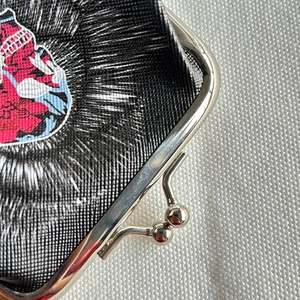 Macro shot of embroidered black fabric coin purse with vintage metal clasp closure