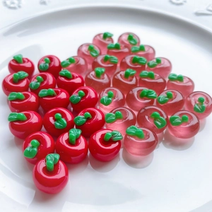 Macro shot of miniature red and pink resin apple charms arranged in a heart shape on a plate