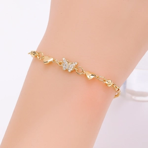 Detail of gold butterfly bracelet with pavé rhinestones and heart charms on wrist