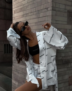 Detail of white satin loungewear set with black print against a red brick wall