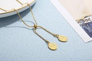 Macro detail of golden snake chain necklace featuring oval religious relief pendants