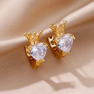 Macro shot of gold crown earrings featuring heart-shaped cubic zirconia on satin fabric