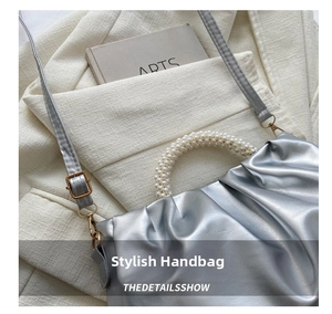 Detailed close-up of a silver pleated cloud bag with elegant pearl beaded handle