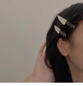 Detail view of two mini silver dagger hair clips worn on black hair for a punk style