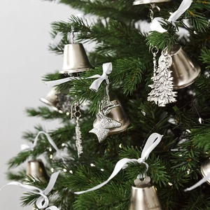 Vintage iron Christmas bells with deer pendants hanging on a green Xmas tree branch