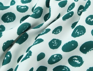 Detailed macro shot of white chiffon fabric with green polka dot print pattern