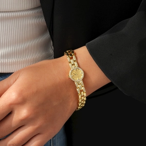 Dettaglio di un orologio placcato oro 18k con lunetta in zirconi e cinturino sottile in metallo