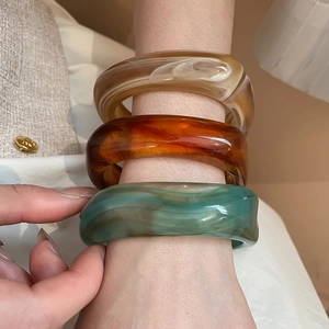 Macro shot of oversized acrylic resin bangles with marble texture in amber and teal