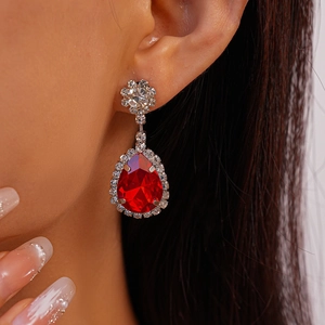 Gros plan d'élégantes boucles d'oreilles goutte rouges avec clous fleuris en diamant