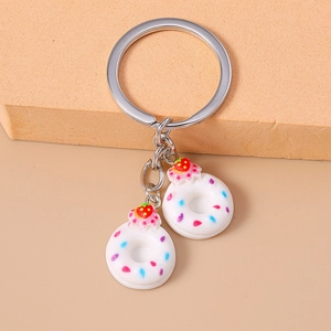 Detailed view of metal keychain featuring two white donuts with pink icing and sprinkles