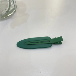 Detail view of a dark green matte oval hair clip on a clean white background