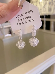 Detailed macro view of vintage pearl drop earrings with elegant silver crown lace setting