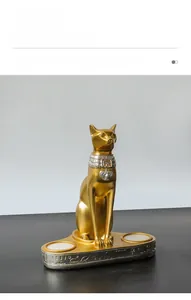 Dettaglio della statua di gatto Bastet dorata con geroglifici e doppio candeliere