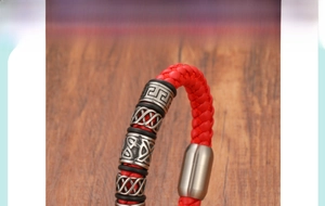 Détail d'un bracelet en cuir tressé rouge avec perles en métal vintage et fermoir magnétique