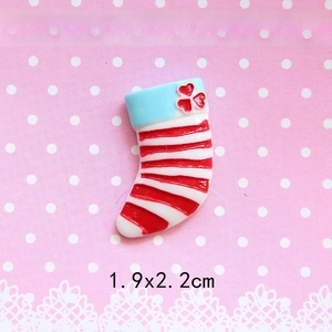 Detail view of a 1.9x2.2cm Christmas stocking resin charm with red stripes and blue cuff